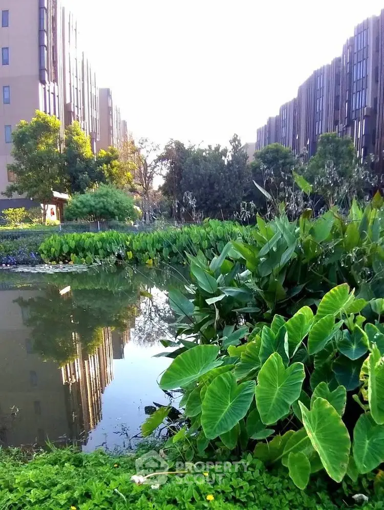 Stunning view of modern apartment buildings with lush greenery and serene pond.