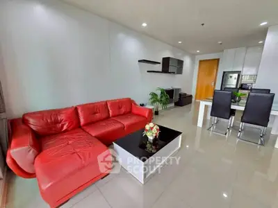 Modern living room with red sofa and sleek dining area in open layout apartment.