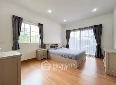 Spacious bedroom with modern furnishings and large windows for natural light.