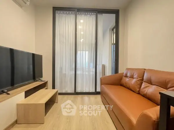 Modern living room with leather sofa and large TV, featuring elegant wooden flooring.