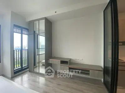 Modern bedroom with large windows and built-in storage in a high-rise apartment.