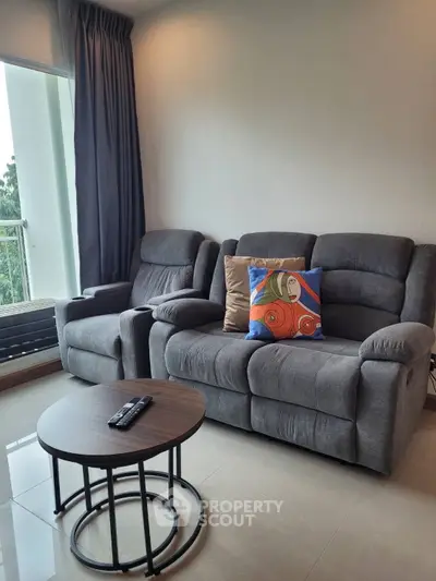 Cozy living room with plush gray recliners and a vibrant cushion, perfect for relaxation.