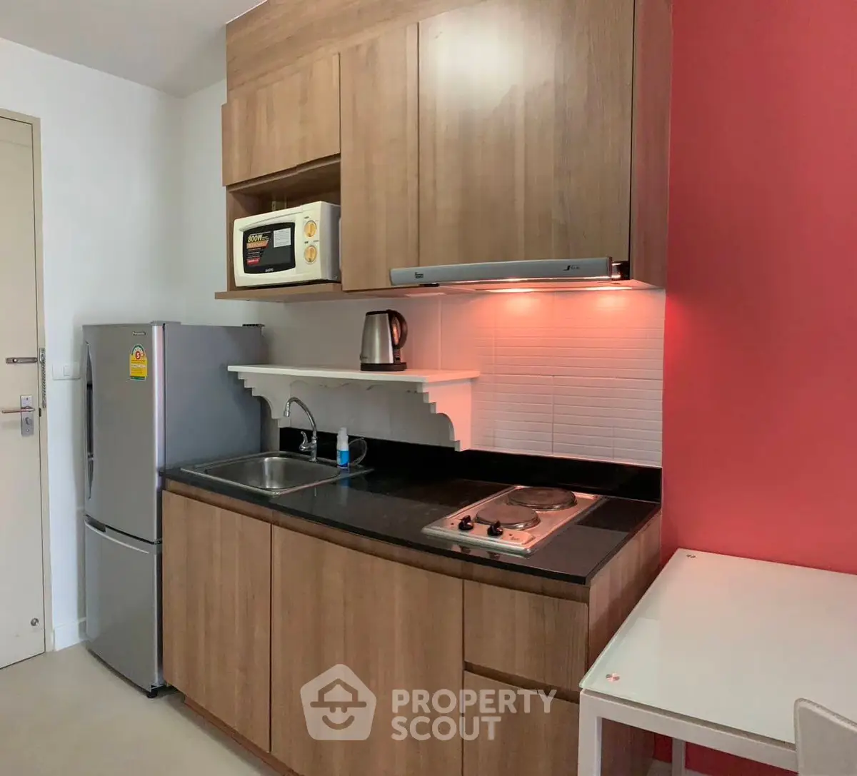Modern compact kitchen with wooden cabinets and red accent wall