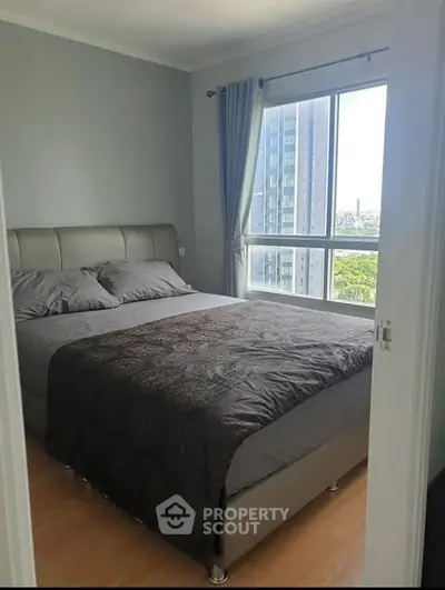 Modern bedroom with large window and city view in high-rise apartment