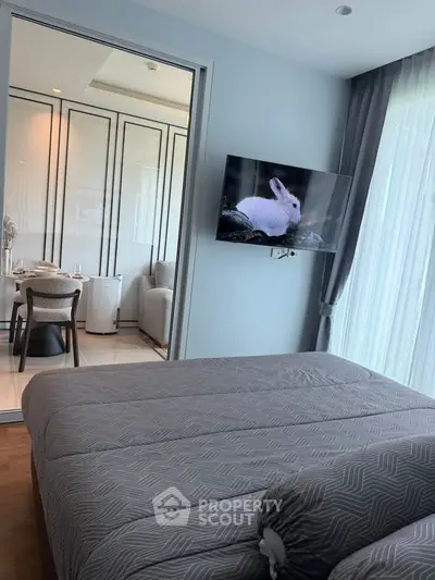 Modern bedroom with stylish decor and a view into a chic dining area.