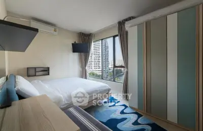 Modern bedroom with large window and city view, featuring stylish decor and ample natural light.