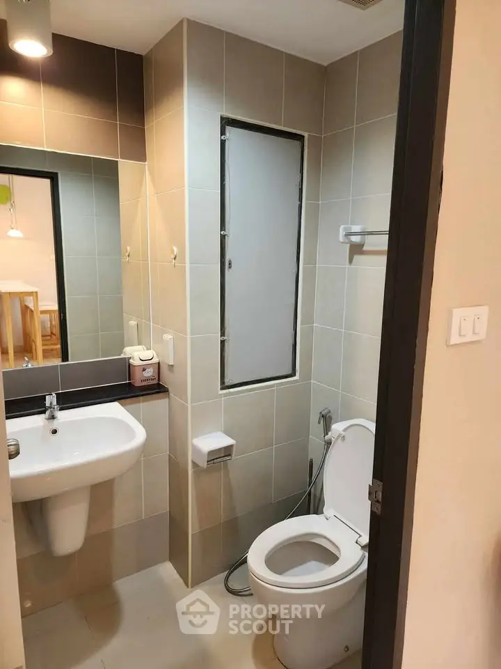 Modern bathroom with sleek fixtures and neutral tiles, featuring a wall-mounted sink and toilet.