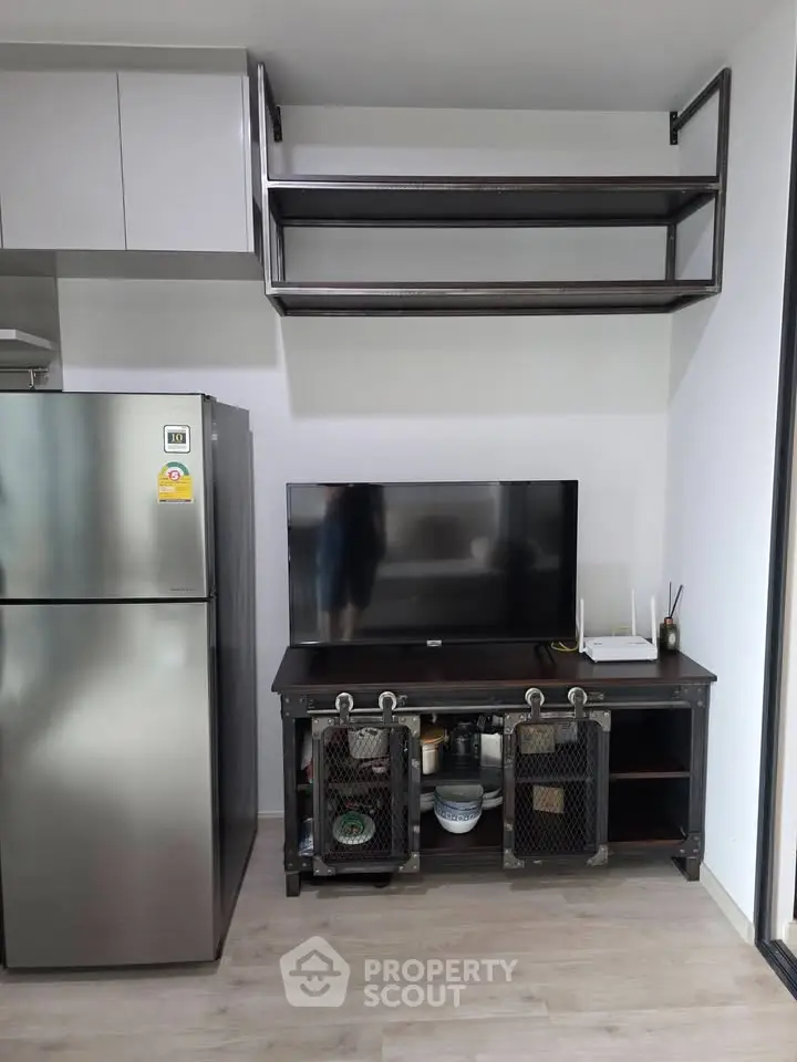 Modern kitchen with sleek fridge and industrial-style shelving and TV stand.