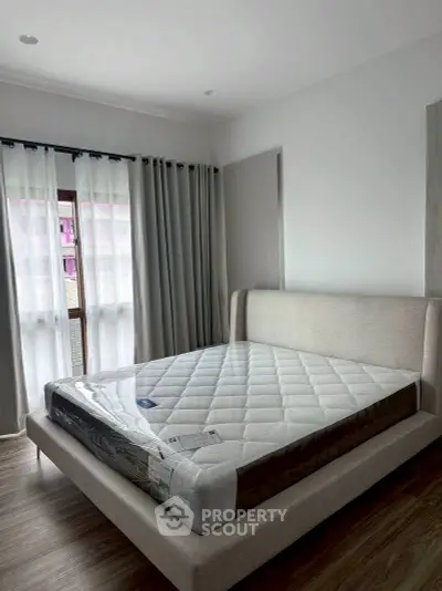 Spacious bedroom with elegant bed and natural light through large windows.