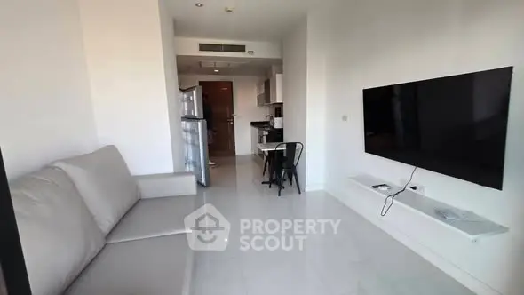 Modern living room with sleek furniture and wall-mounted TV in a bright apartment.