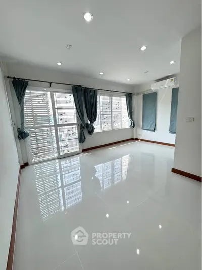 Spacious empty living room with large windows and modern lighting