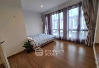 Spacious bedroom with large windows and wooden flooring in modern home.