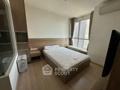Modern bedroom with large window and wooden flooring, featuring a comfortable bed and air conditioning.