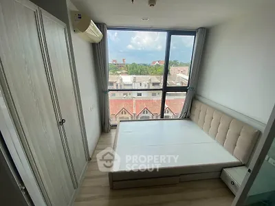 Modern bedroom with large window offering city view, featuring built-in wardrobe and air conditioning.