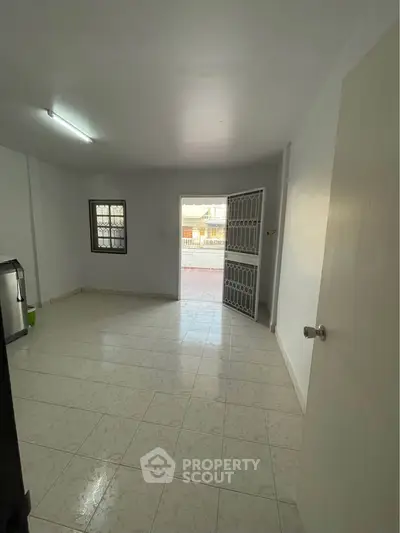 Spacious room with tiled flooring and open door leading to outdoor area, ideal for versatile use.