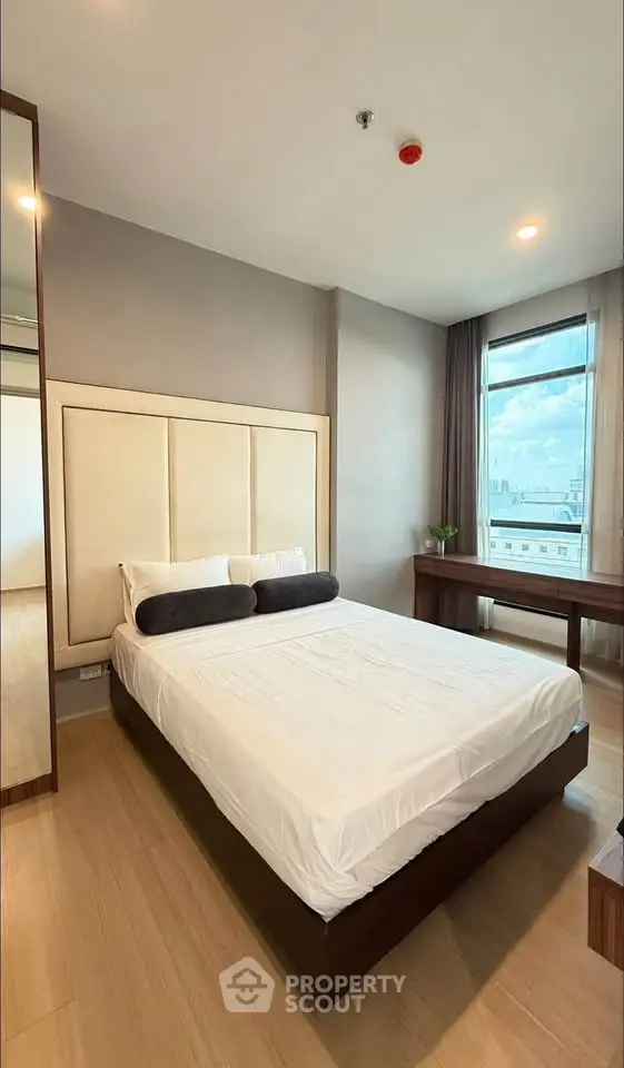 Modern bedroom with city view, featuring a stylish bed and elegant decor.