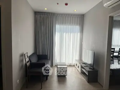 Modern living room with sleek furniture and large window offering natural light.