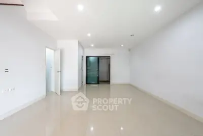 Spacious empty room with glossy tiled flooring and bright lighting.