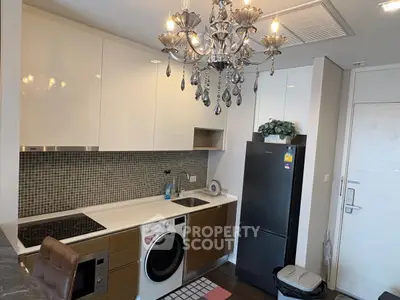 Modern kitchen with chandelier, washing machine, and sleek cabinetry.