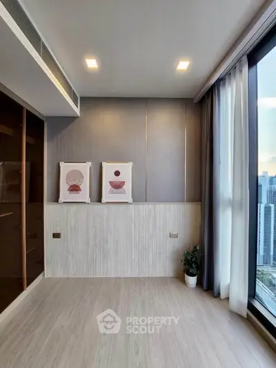 Modern living room with large windows and city view, featuring elegant wall art and sleek flooring.