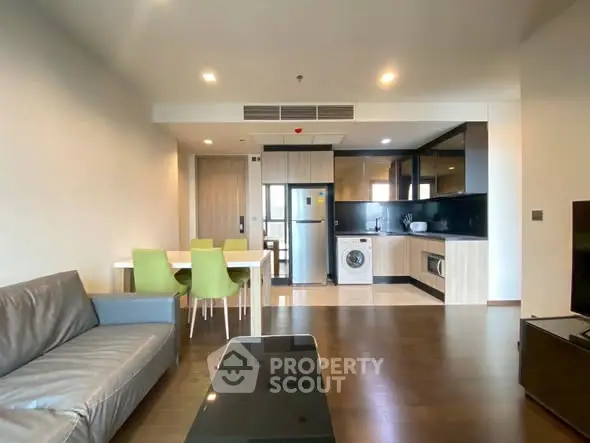 Modern open-plan living room with kitchen, featuring sleek furniture and appliances.