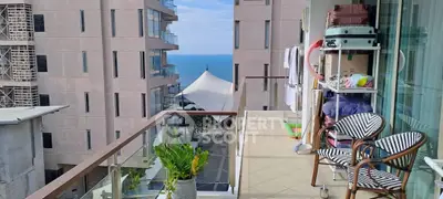 Charming balcony with ocean view, stylish chairs, and lush plant, perfect for relaxation.