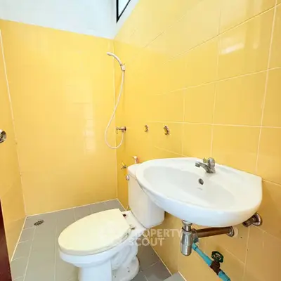 Compact bathroom with yellow tiles and basic fixtures