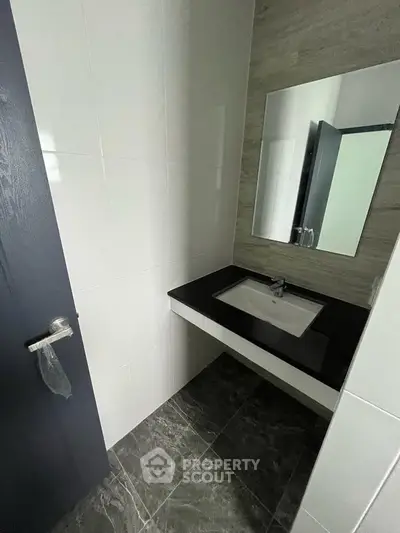 Modern bathroom with sleek black countertop and stylish mirror in a contemporary home.