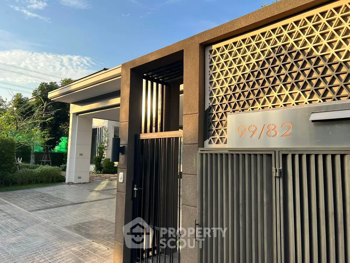 Modern gated entrance with stylish design and geometric patterns in a residential area.