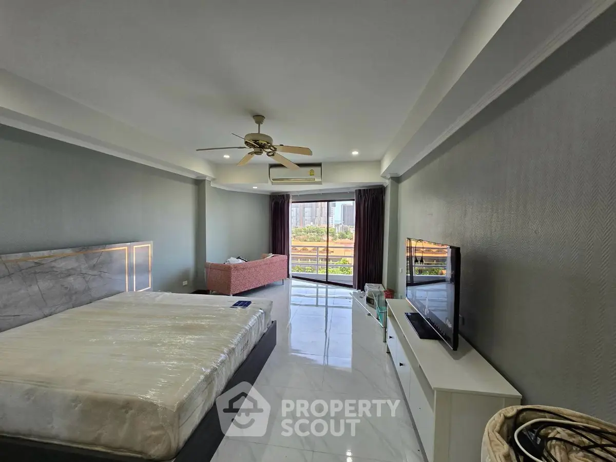 Spacious bedroom with modern decor and balcony view in luxury apartment