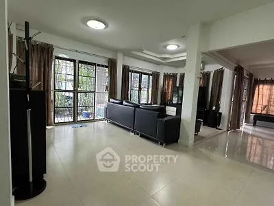 Spacious living room with modern black leather sofas and large windows offering natural light.