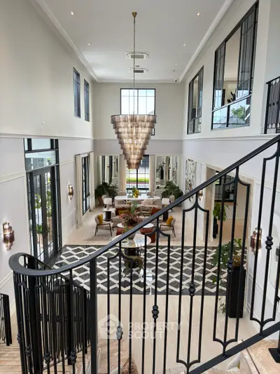 Luxurious living room with grand staircase and elegant chandelier in a spacious open layout.
