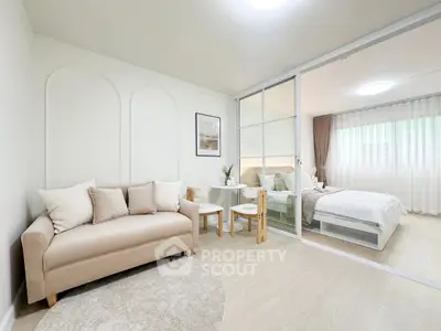 Modern open-plan living room and bedroom with stylish decor and neutral tones.