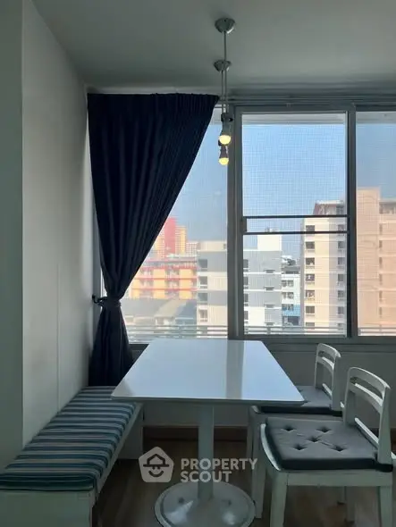 Bright dining area with city view, featuring modern table and chairs by large window.