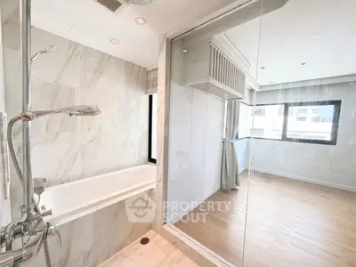 Modern bathroom with glass partition and elegant bathtub in bright apartment