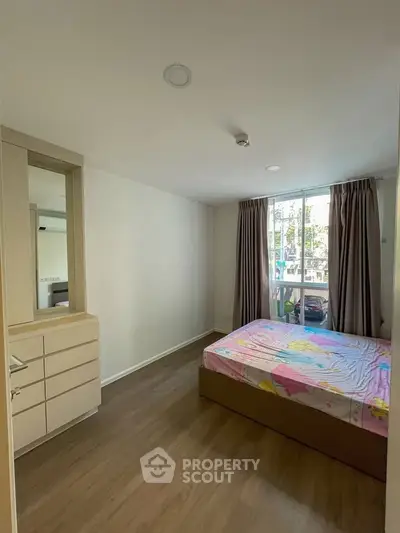 Cozy bedroom with natural light and modern furnishings in a stylish apartment.