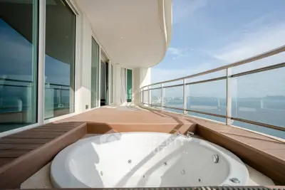 Luxurious balcony with jacuzzi and stunning ocean view in modern high-rise apartment.