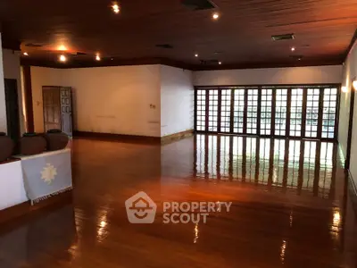 Spacious wooden-floored room with large windows and warm lighting, ideal for gatherings.