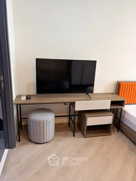 Modern bedroom with sleek TV stand and cozy seating in stylish apartment.