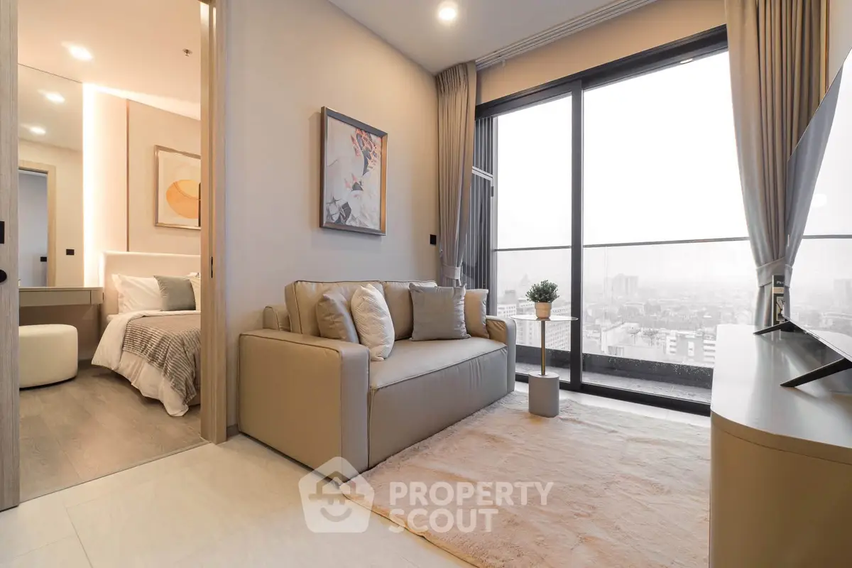 Modern living room with cozy sofa and city view from large windows in high-rise apartment.