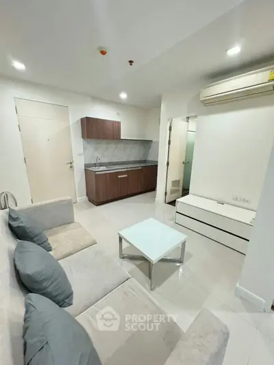 Modern living room with sleek furniture and compact kitchen area, perfect for urban living.