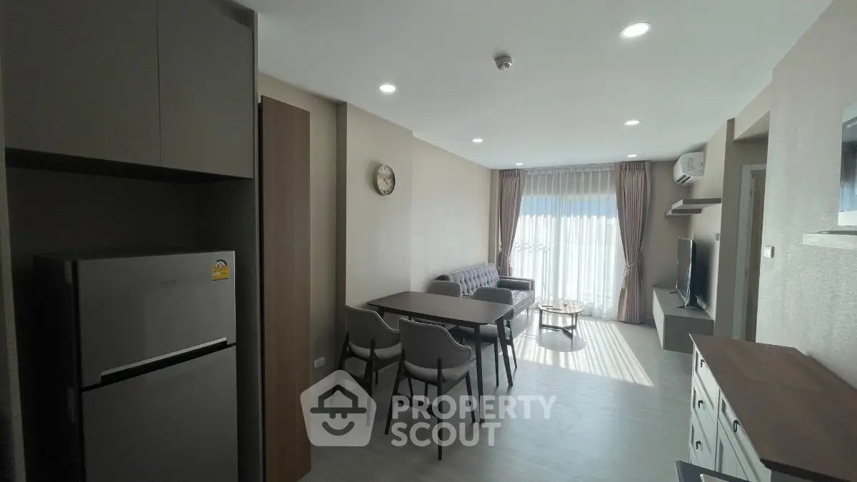 Modern living room with dining area, featuring sleek furniture and natural light.