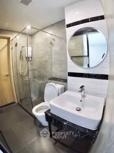 Modern bathroom with glass shower and sleek fixtures in contemporary apartment.