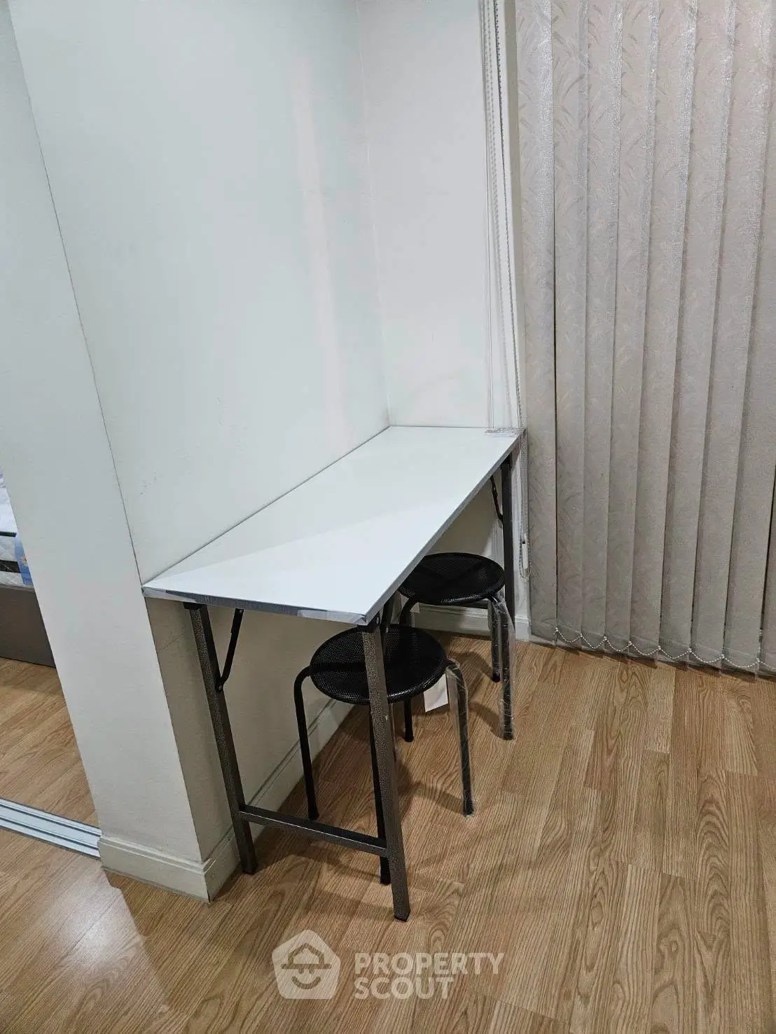 Compact study nook with sleek white desk and stools, perfect for small spaces.