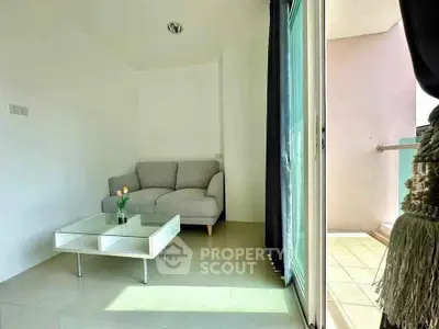 Bright living room with cozy sofa and glass coffee table, adjacent to a sunny balcony.