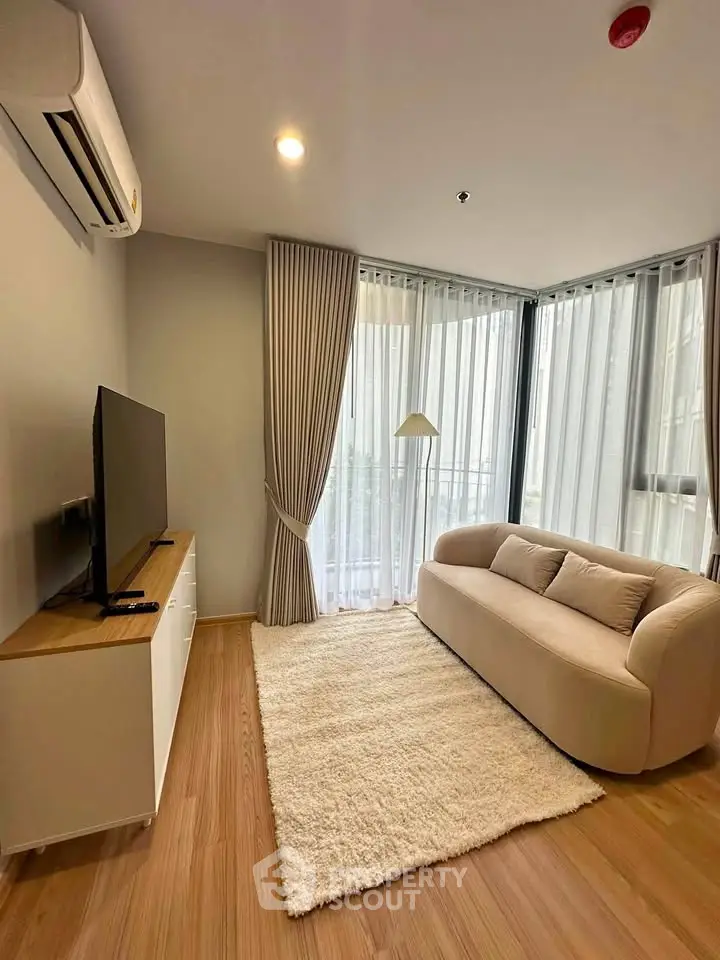 Modern living room with cozy sofa, TV, and large windows with curtains in a stylish apartment.