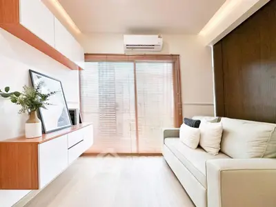 Modern living room with sleek design, featuring a cozy sofa, stylish shelves, and natural light through large windows.