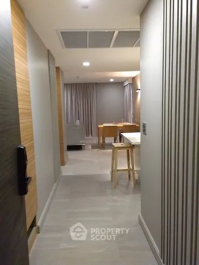 Modern apartment hallway leading to a cozy living area with stylish decor and neutral tones.