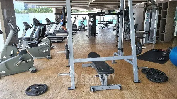 Spacious modern gym with state-of-the-art equipment and wooden flooring in a luxury property.