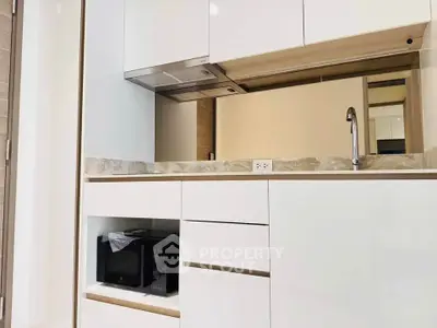 Modern kitchen with sleek white cabinetry and built-in microwave, perfect for contemporary living.